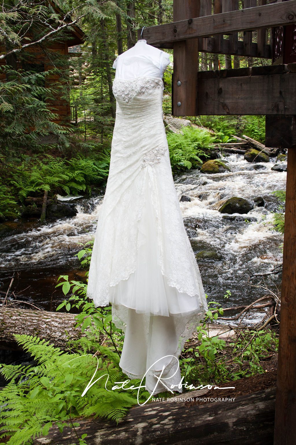 Bride's dress hanging in the trees with waterfall behind it at Elkins Resort Wedding
