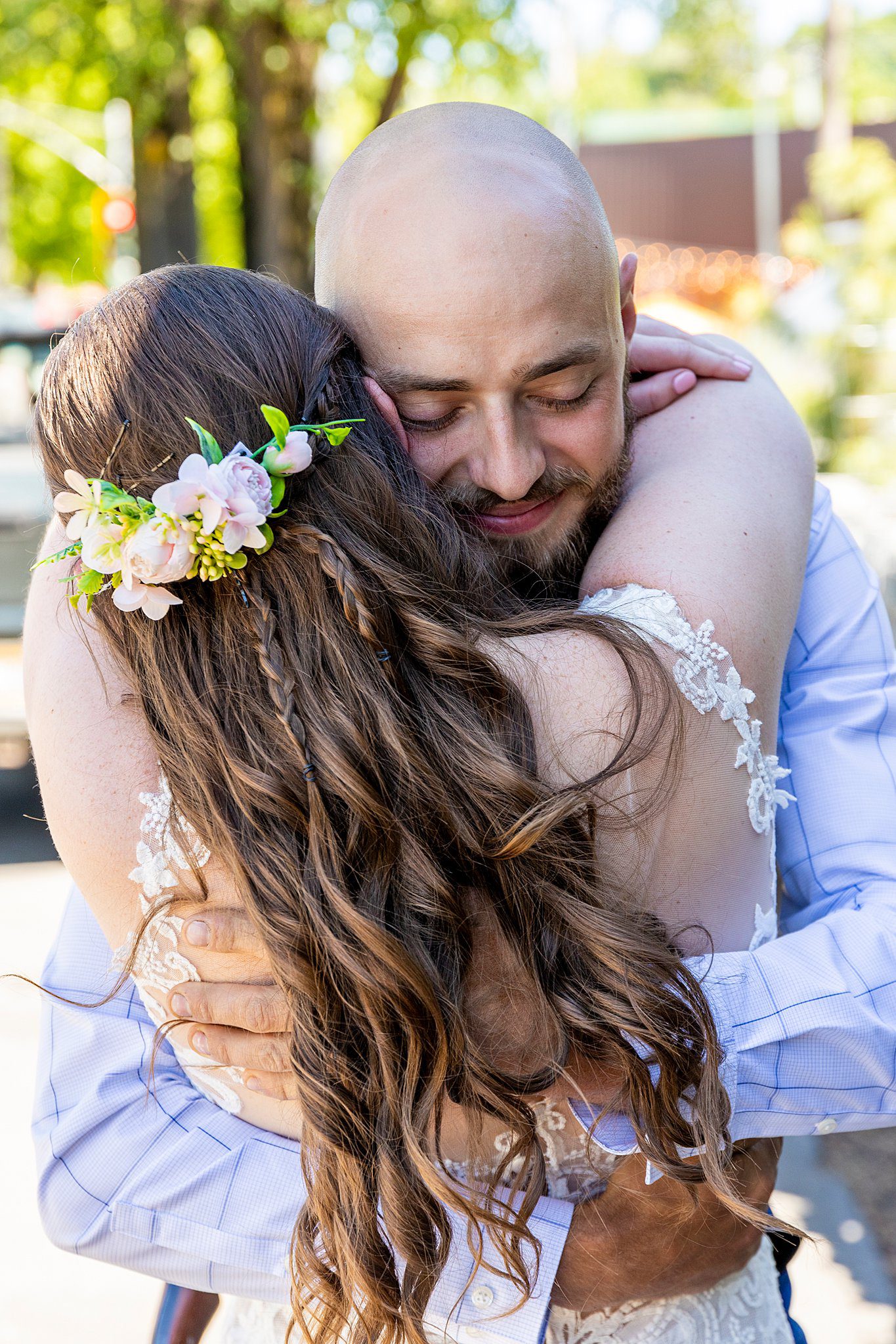 groom hugs his bride wearing a flower head piece and white lace dress at aspen grove wedding