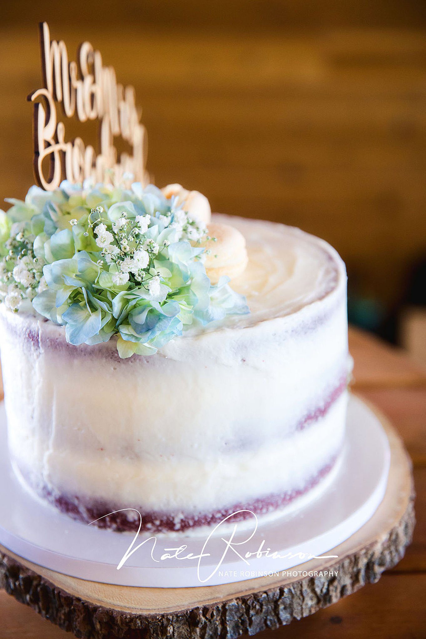 wedding cake with flower and food topper sits on a live edge oak setting at a palouse knot barn wedding