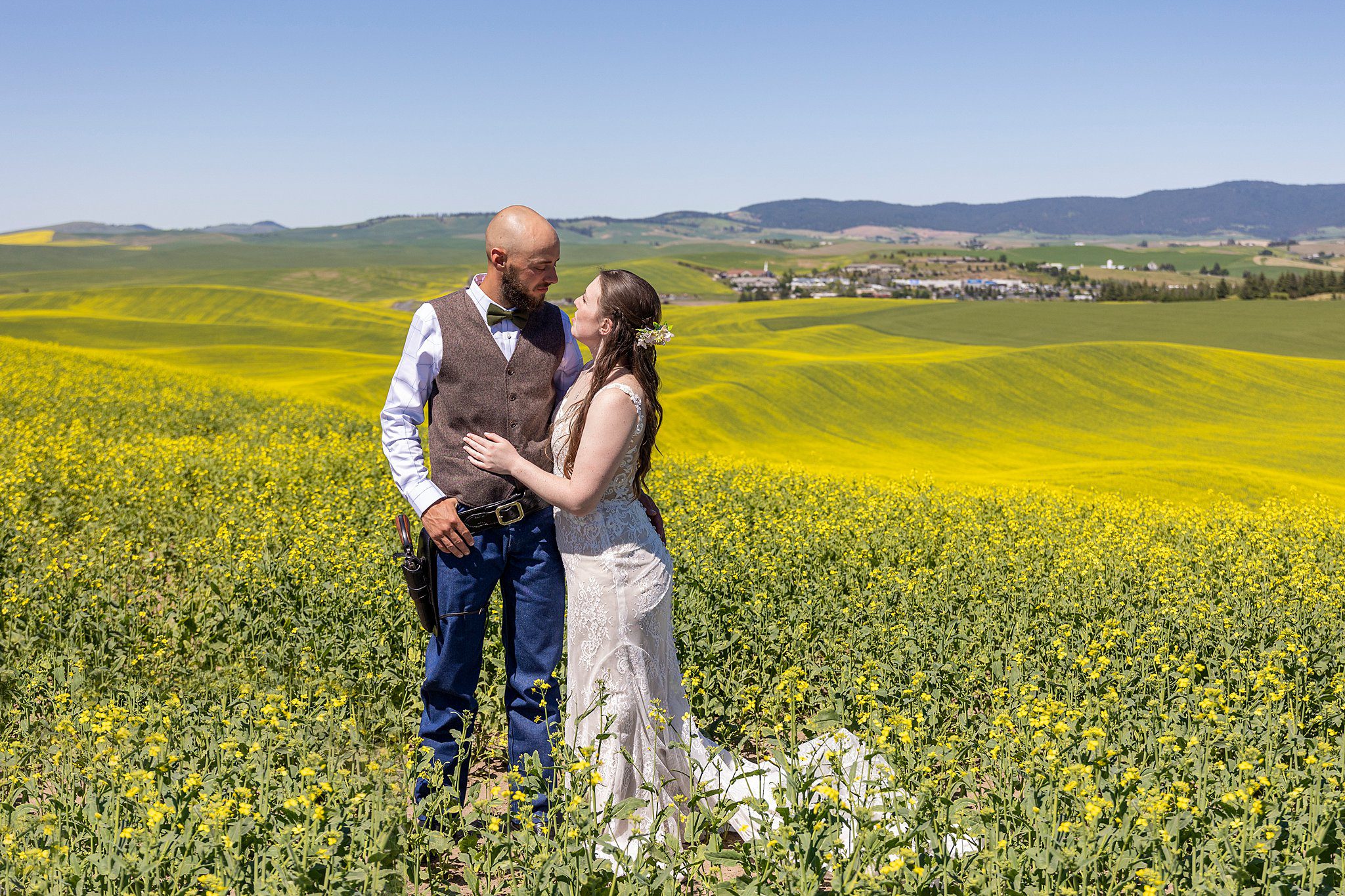 Newlyweds embrace on a hill surrounded by open rolling fields of yellow wildflowers silverbell wedding