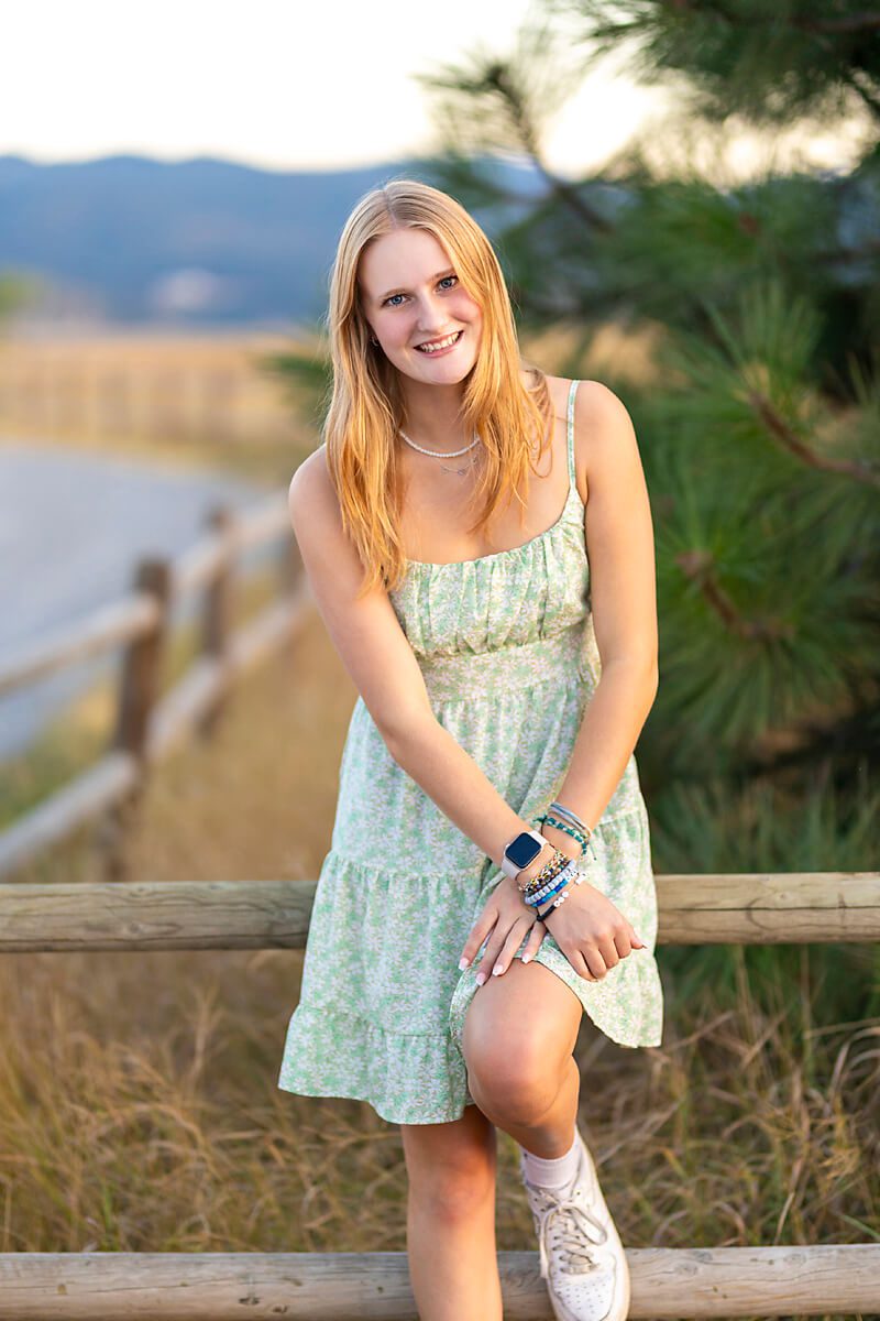 blonde girl wearing a sundress for fall senior photos in a natural setting